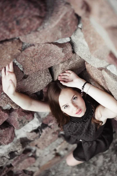 Bela triste jovem mulher em um fundo de parede de pedra — Fotografia de Stock