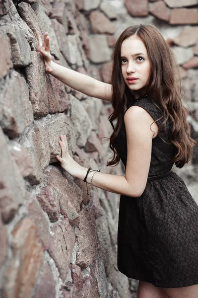 Mooie triest jonge vrouw op een stenen muur achtergrond — Stockfoto