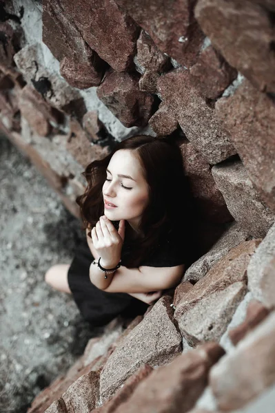 Bela triste jovem mulher em um fundo de parede de pedra — Fotografia de Stock