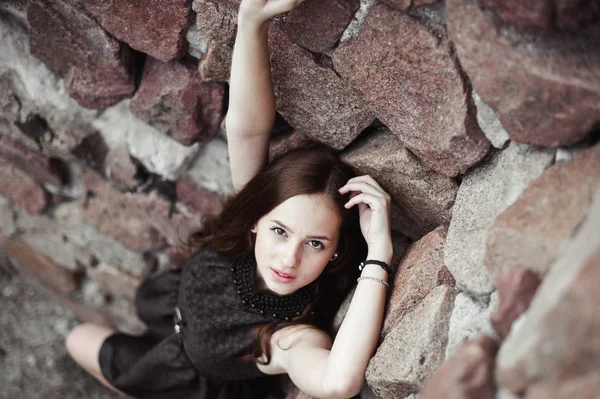 Vackra sorgliga ung kvinna på en stenmur bakgrund — Stockfoto