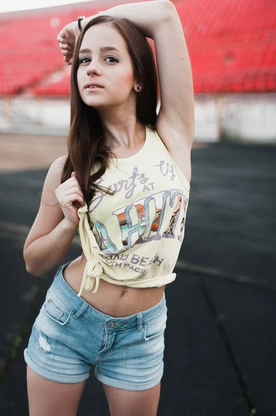 Menina se divertindo ao ar livre. Menina bonita sentada no estádio da escola . — Fotografia de Stock