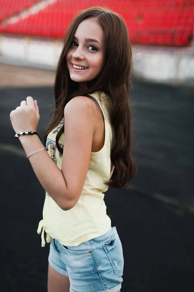 Ragazza divertirsi all'aperto. Bella ragazza seduta allo stadio della scuola . — Foto Stock