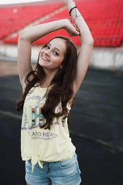 Meisje met plezier buiten. Mooi meisje zit op school stadion. — Stockfoto