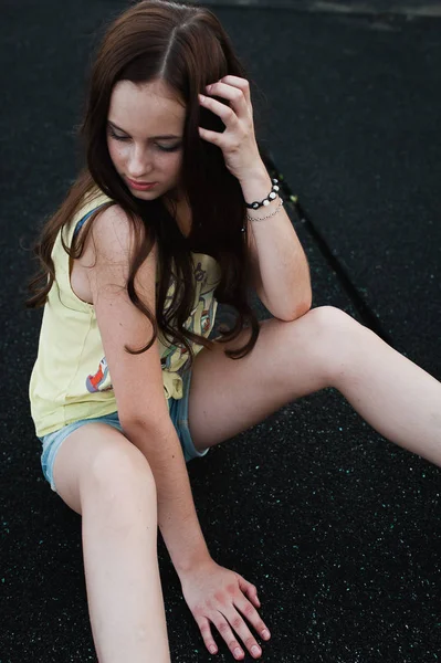 Hermosa chica hipster joven sentado en el medio de asfalto ro — Foto de Stock