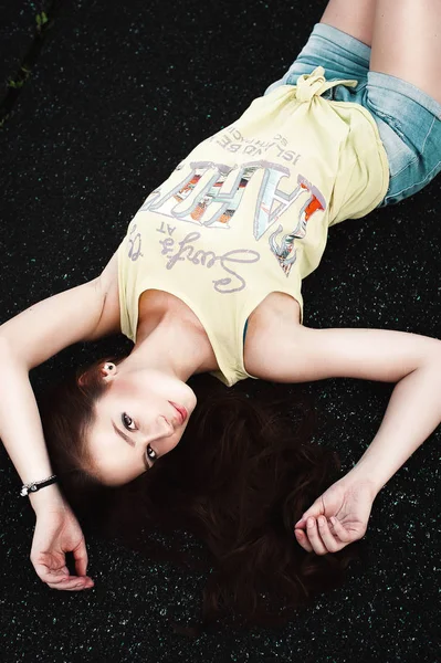 Красива молода хіпстерська дівчина лежить посеред асфальтової дороги , — стокове фото