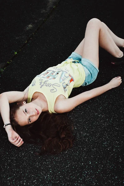 Красива молода хіпстерська дівчина лежить посеред асфальтової дороги , — стокове фото