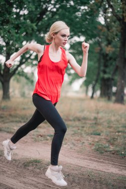Genç bir kadın parkta koşuyor.