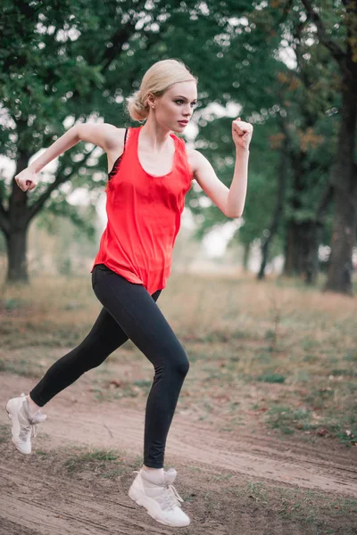 Genç bir kadın parkta koşuyor.