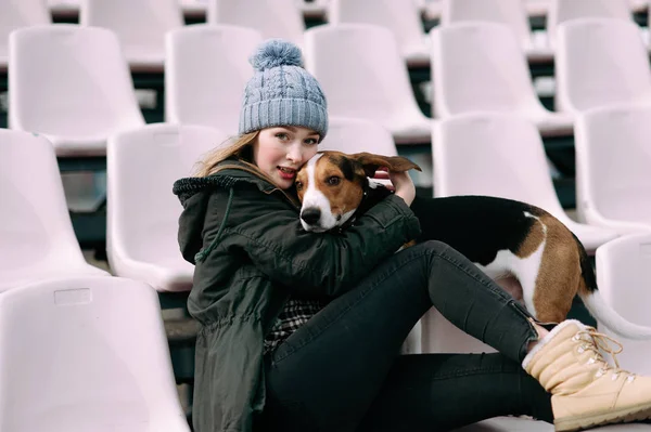 Молода дівчина-хіпстер зі своїм домашнім улюбленцем Естонська собака, грає, перев'язується і обіймається і розважається на стадіоні . — стокове фото