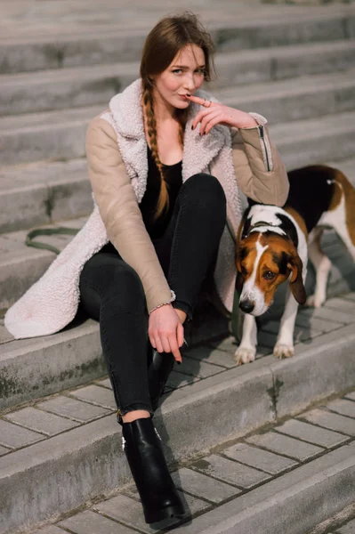 Menina jovem hipster com seu animal de estimação cão de caça estoniano jogando e se divertindo ao ar livre no parque . — Fotografia de Stock