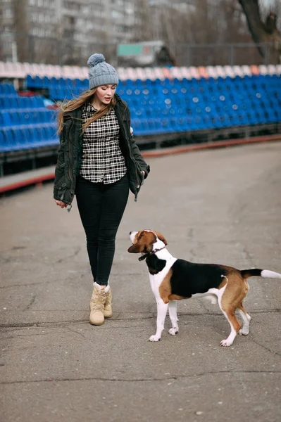 Молодая девушка-хипстер со своей собакой-эстонкой, играющая, обнимающая и развлекающаяся на открытом воздухе на старом стадионе . — стоковое фото
