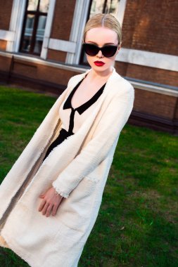 Mutlu moda sarışın Avrupa zarif kadın kırmızı dudakları ve beyaz ayakta yeşil çimenlerin üzerinde bina eski kırmızı tuğla, Cilt. Seksi kız açık havada. Resmi siyah beyaz elbiseli güzel kadın 