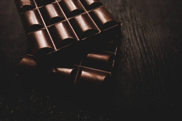 Chocolate na mesa de madeira no fundo escuro — Fotografia de Stock