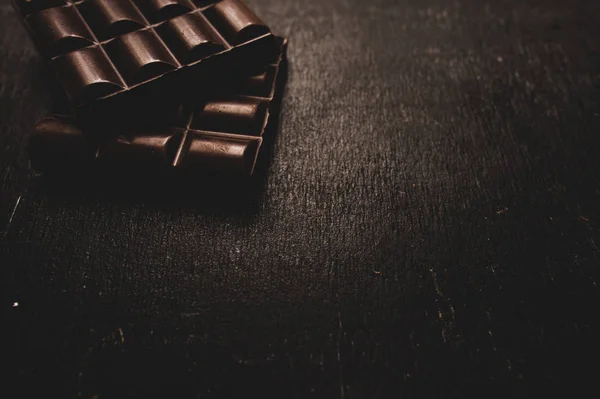 Chocolate na mesa de madeira no fundo escuro — Fotografia de Stock