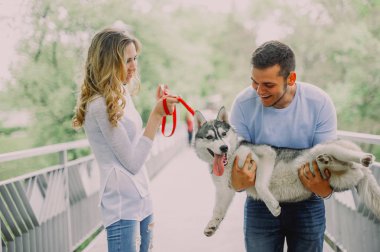 Güzel genç çift bir parkta husky köpeğiyle oynuyor. Summe
