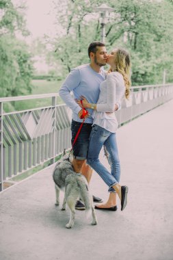 Güzel genç çift bir parkta husky köpeğiyle oynuyor. Yaz açık havada.