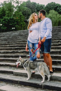 Güzel genç çift bir parkta husky köpeğiyle oynuyor. Summe