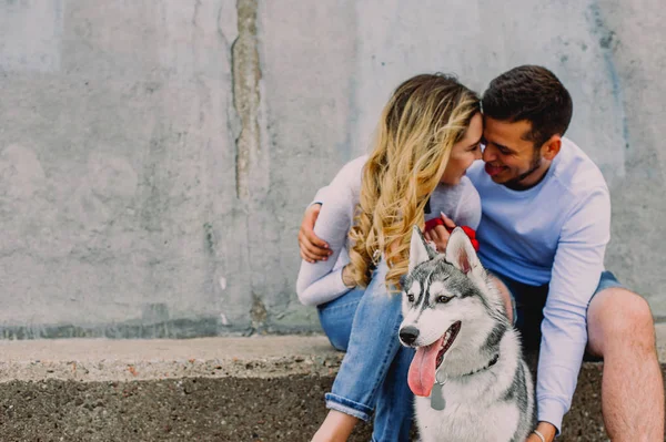 Schönes junges Paar, das mit einem Husky-Hund in einem Park spielt. Summen — Stockfoto