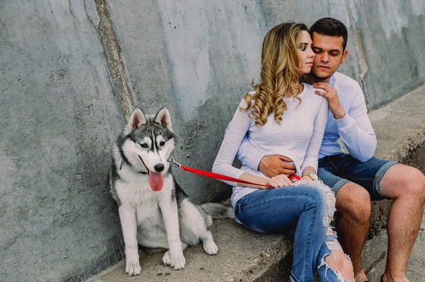 Schönes junges Paar, das mit einem Husky-Hund in einem Park spielt. Sommer im Freien. — Stockfoto