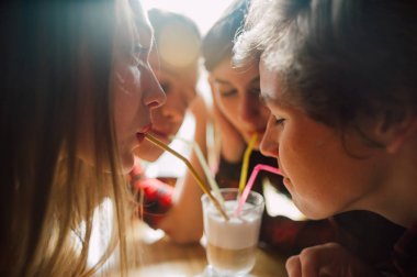 Grup genç arkadaşlar bir kahve dükkanında dışarı asılı. Genç erkek ve kadınların bir kafede kahve içme ve eğlenmek tanışmak. Yaşam tarzı, dostluk ve kentsel yaşam kavramları.