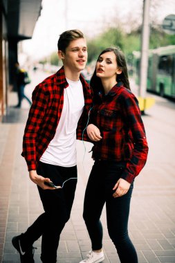 Kulaklık ile müzik dinlemek, birbirlerine söz ve gülümseyen yürüyüş ve şehirde dans iki mutlu trendy genç arkadaş. Yaşam tarzı, dostluk ve kentsel yaşam kavramları.