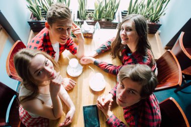 Grup genç arkadaşlar bir kahve dükkanında dışarı asılı. Genç erkek ve kadınların bir kafede kahve içme ve eğlenmek tanışmak. Yaşam tarzı, dostluk ve kentsel yaşam kavramları.