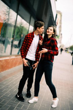 Kulaklık ile müzik dinlemek, birbirlerine söz ve gülümseyen yürüyüş ve şehirde dans iki mutlu trendy genç arkadaş. Yaşam tarzı, dostluk ve kentsel yaşam kavramları.