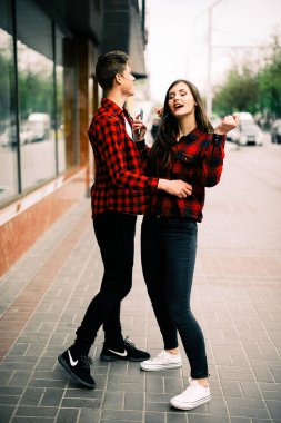 Kulaklık ile müzik dinlemek, birbirlerine söz ve gülümseyen yürüyüş ve şehirde dans iki mutlu trendy genç arkadaş. Yaşam tarzı, dostluk ve kentsel yaşam kavramları.