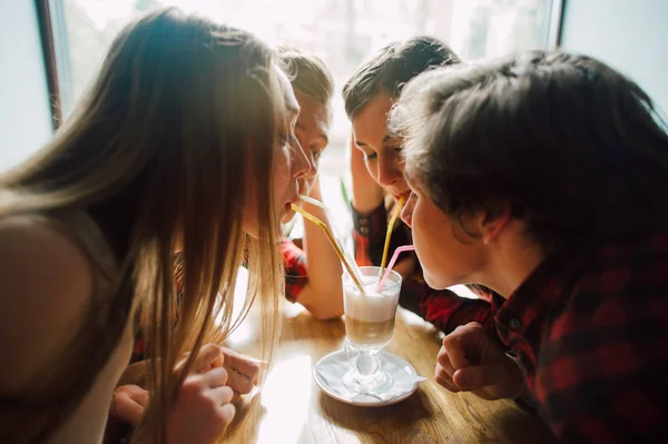 Un grupo de jóvenes amigos pasando el rato en una cafetería. Hombres y mujeres jóvenes que se reúnen en un café divirtiéndose y tomando café. Conceptos de estilo de vida, amistad y vida urbana . — Foto de Stock