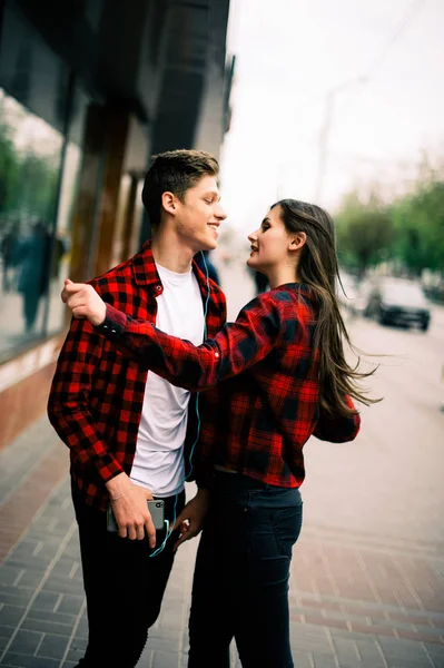 Två glada trendiga tonåriga vänner promenader och dans i staden, lyssna på musik med hörlurar, prata varandra och ler. Livsstil, vänskap och stadslivet begrepp. — Stockfoto