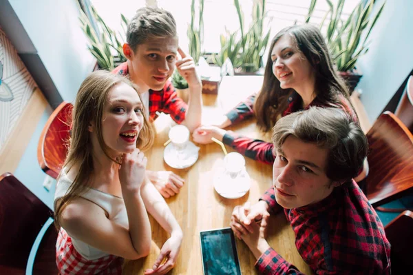 Un grupo de jóvenes amigos pasando el rato en una cafetería. Hombres y mujeres jóvenes que se reúnen en un café divirtiéndose y tomando café. Conceptos de estilo de vida, amistad y vida urbana . — Foto de Stock