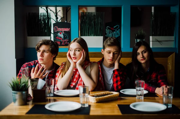 Un grupo de jóvenes amigos pasando el rato en una cafetería. Hombres y mujeres jóvenes que se reúnen en un café divirtiéndose y tomando café. Conceptos de estilo de vida, amistad y vida urbana . — Foto de Stock