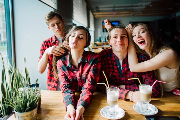 Gruppen av unga vänner umgås på ett kafé. Unga män och kvinnor möte på ett café att ha kul och dricka kaffe. Livsstil, vänskap och stadslivet begrepp. — Stockfoto