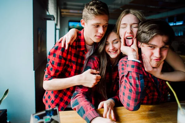 Un grupo de jóvenes amigos pasando el rato en una cafetería. Hombres y mujeres jóvenes que se reúnen en un café divirtiéndose y tomando café. Conceptos de estilo de vida, amistad y vida urbana . — Foto de Stock