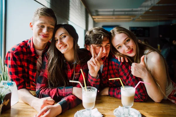 Un grupo de jóvenes amigos pasando el rato en una cafetería. Hombres y mujeres jóvenes que se reúnen en un café divirtiéndose y tomando café. Conceptos de estilo de vida, amistad y vida urbana . — Foto de Stock