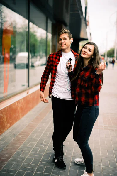 Två glada trendiga tonåriga vänner promenader och dans i staden, lyssna på musik med hörlurar, prata varandra och ler. Livsstil, vänskap och stadslivet begrepp. — Stockfoto