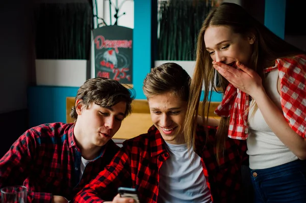 Un grupo de jóvenes amigos pasando el rato en una cafetería. Hombres y mujeres jóvenes que se reúnen en un café divirtiéndose y tomando café. Conceptos de estilo de vida, amistad y vida urbana . — Foto de Stock