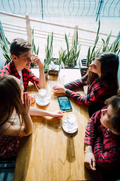 Un grupo de jóvenes amigos pasando el rato en una cafetería. Hombres y mujeres jóvenes que se reúnen en un café divirtiéndose y tomando café. Conceptos de estilo de vida, amistad y vida urbana . — Foto de Stock