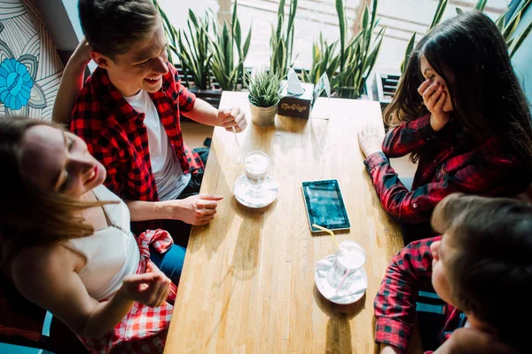 コーヒー ショップで時間を過ごす若い友人のグループです。若い男性と女性がコーヒーを飲むと楽しいカフェで会議します。ライフ スタイル、友情や都市生活の概念. — ストック写真