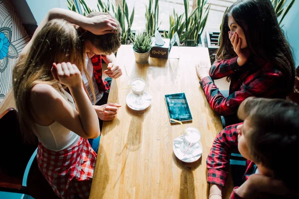 Un grupo de jóvenes amigos pasando el rato en una cafetería. Hombres y mujeres jóvenes que se reúnen en un café divirtiéndose y tomando café. Conceptos de estilo de vida, amistad y vida urbana . — Foto de Stock