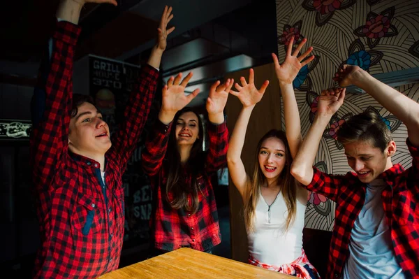 Un grupo de jóvenes amigos pasando el rato en una cafetería. Hombres y mujeres jóvenes que se reúnen en un café divirtiéndose y tomando café. Conceptos de estilo de vida, amistad y vida urbana . — Foto de Stock