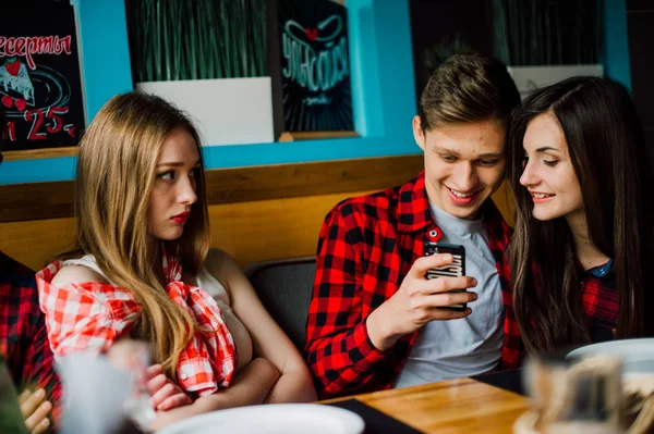 Un grupo de jóvenes amigos pasando el rato en una cafetería. Hombres y mujeres jóvenes que se reúnen en un café divirtiéndose y tomando café. Conceptos de estilo de vida, amistad y vida urbana . — Foto de Stock