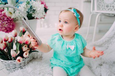 Gülen, gülümseyen, sürünen ve nane elbise stüdyoda oynayan sevimli küçük bebek kız