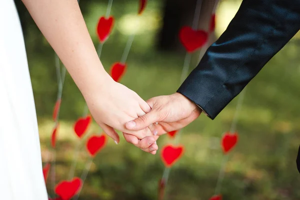 Свадебный букет о поцелуях молодоженов, держащихся за руки — стоковое фото