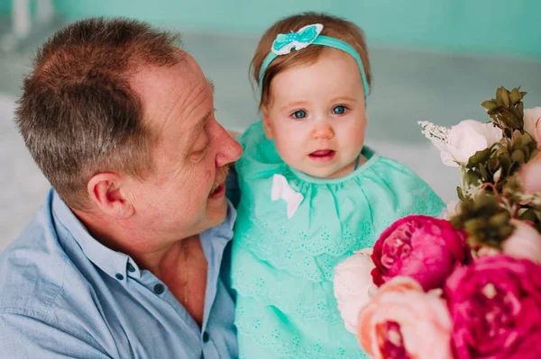 Porträt eines Großvaters im blauen Hemd mit seiner kleinen hübschen Enkelin, die ihn umarmt und aufmerksam zuhört, Studioaufnahme — Stockfoto