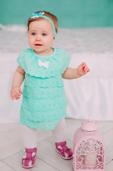 Adorável menina rindo, sorrindo, rastejando e brincando no estúdio vestindo vestido de hortelã — Fotografia de Stock