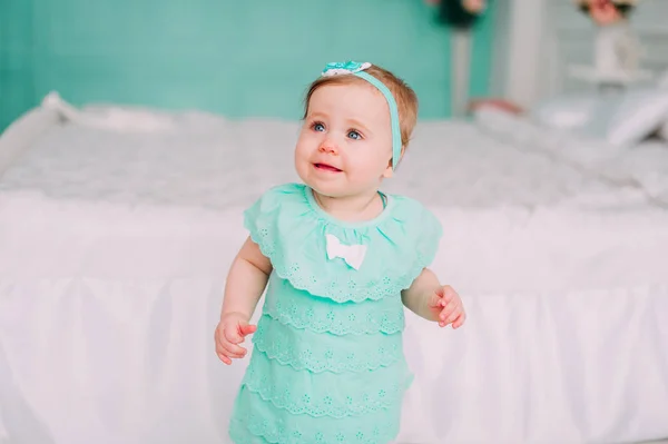 Adorable niña riéndose, sonriendo, arrastrándose y jugando en el estudio con vestido de menta — Foto de Stock