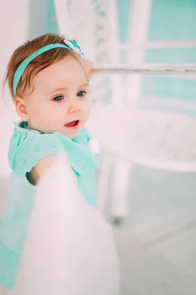 Gülen, gülümseyen, sürünen ve nane elbise stüdyoda oynayan sevimli küçük bebek kız — Stok fotoğraf
