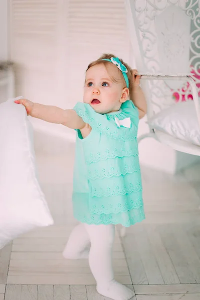 Adorável menina rindo, sorrindo, rastejando e brincando no estúdio vestindo vestido de hortelã — Fotografia de Stock