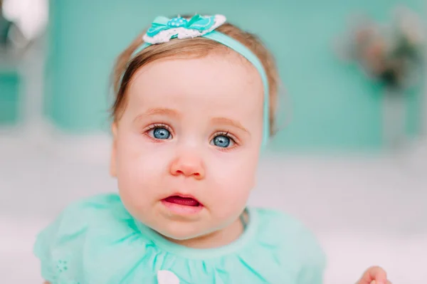 Adorável menina rindo, sorrindo, rastejando e brincando no estúdio vestindo vestido de hortelã — Fotografia de Stock